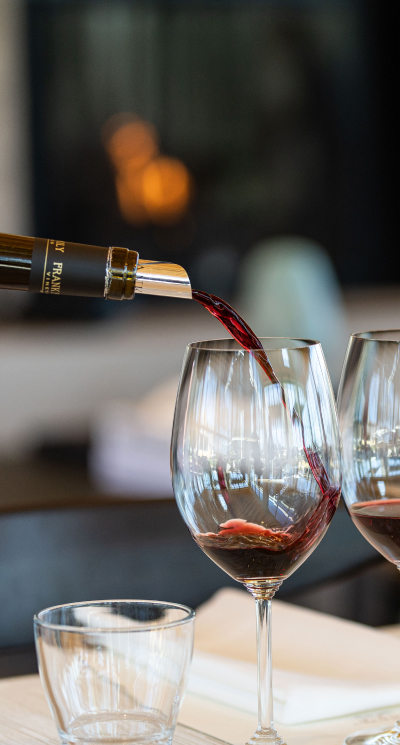 Bottle of wine pouring into glasses.