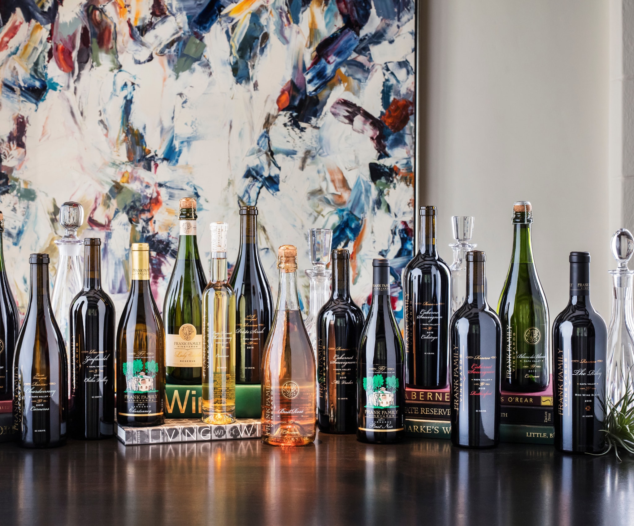 A table with numerous bottles of wine and decorative books.