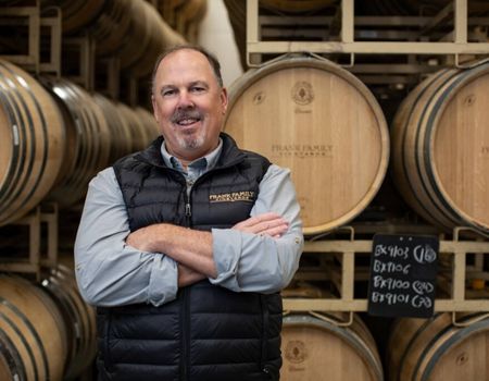 Todd Graff standing in front of racks of wine barrels