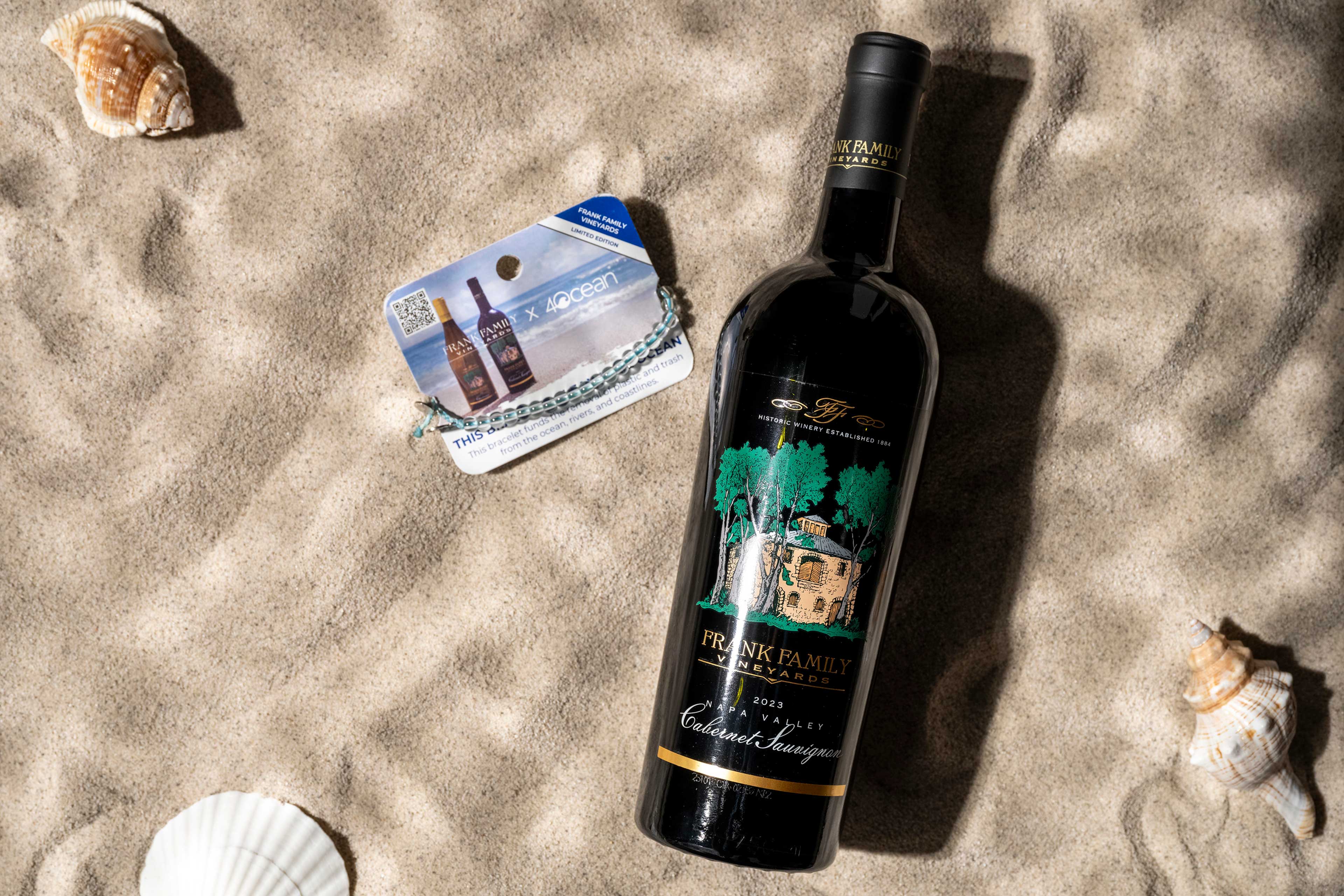 A bottle of Napa Valley Cabernet next to a blue Frank Family x 4ocean bracelet. 