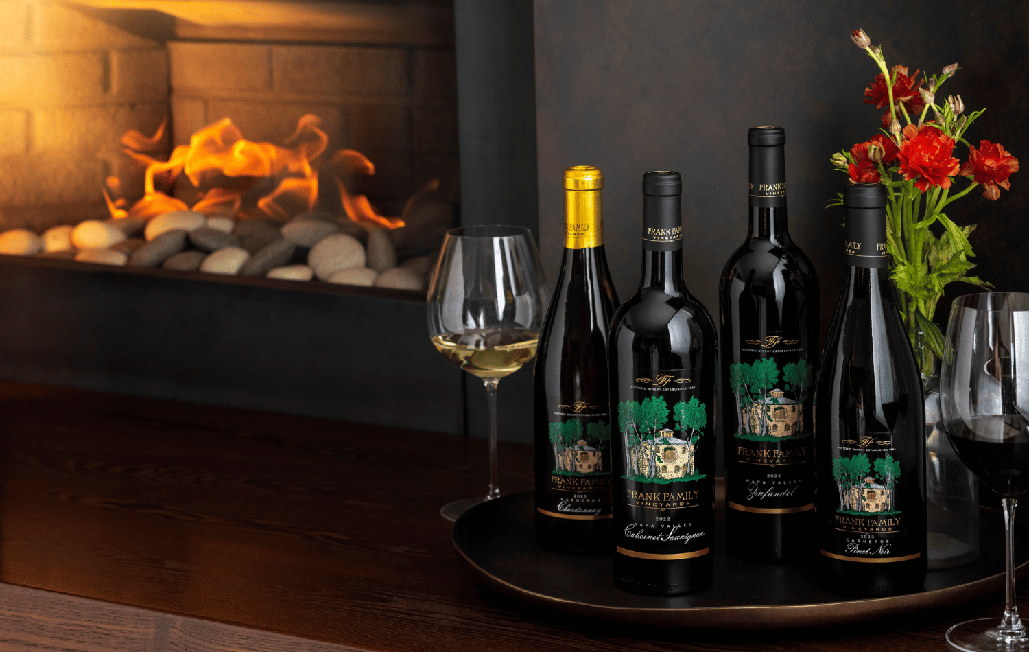 A collection of Chardonnay, Pinot Noir, Zinfandel, and Cabernet set against a fireplace. 